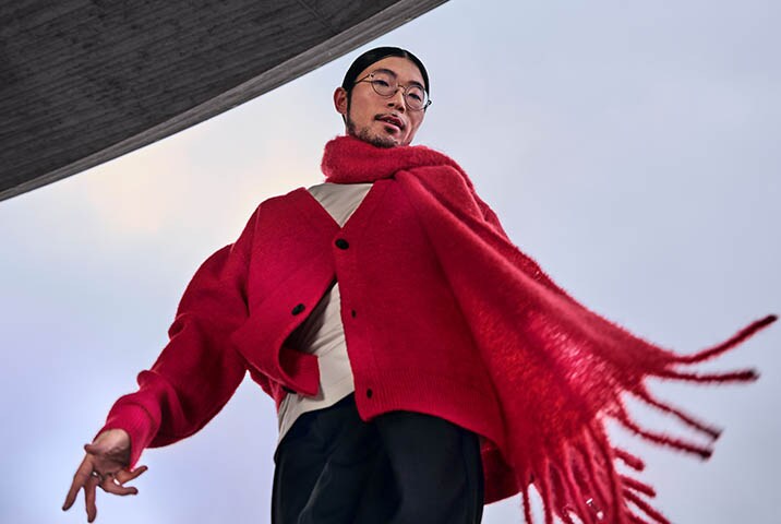 ann mit rotem Wollschal und Cardigan aus Strickstoff in dynamischer Pose – Pflege hochwertiger Textilien mit AEG