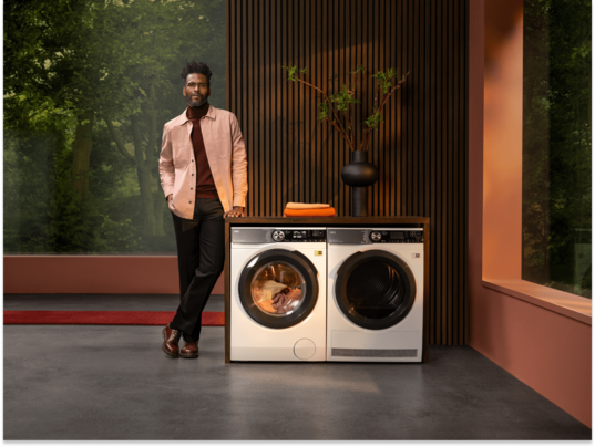Man standing next to laundry machines.
