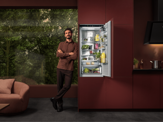 Ein Mann steht neben einem Kühlschrank in einer Küche