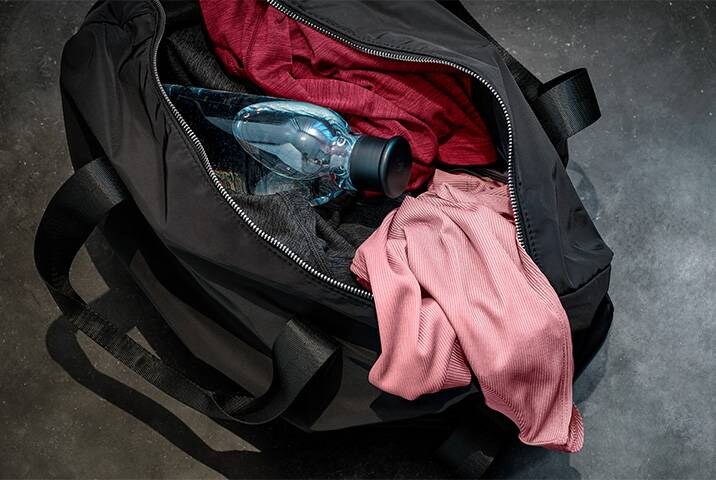 Eine schwarze Tasche mit Sportkleidung und einer Wasserflasche