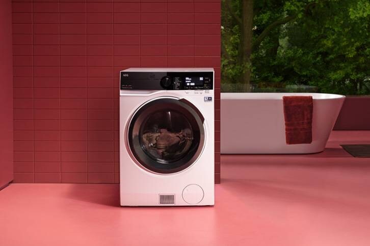 Ein Waschtrockner steht in einer Wochnung, im Hintergrund steht eine moderne Badewanne